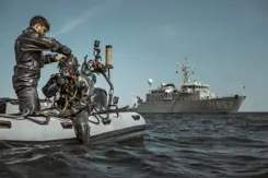 Militair in duikpak op rubberbootje maakt zich klaar voor duik in zee.