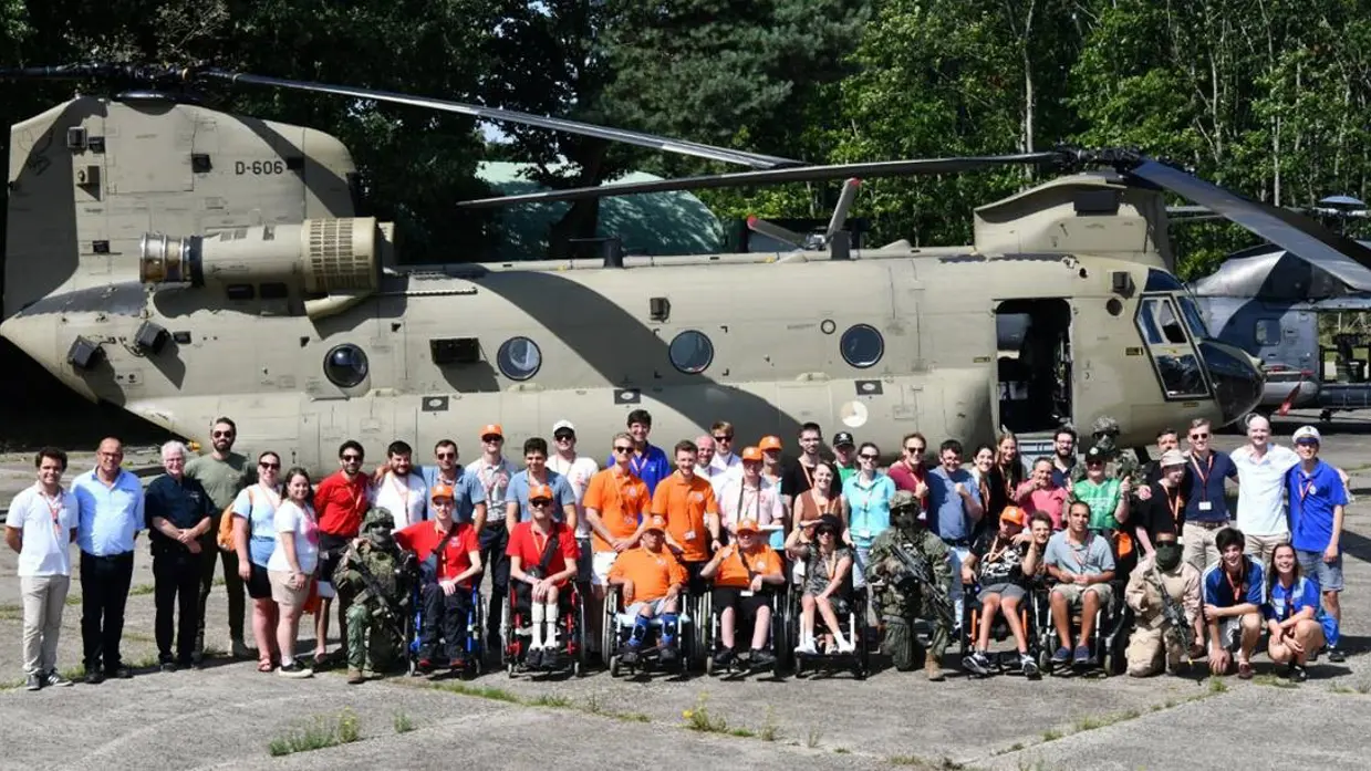 Jongeren staan voor een Apache-gevechtshelikopter.