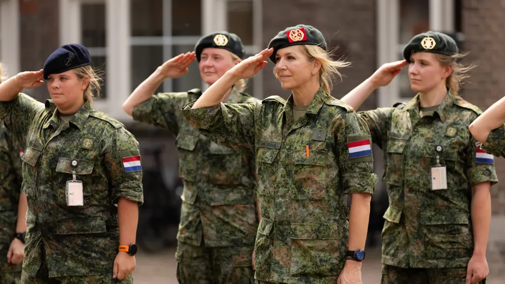 Militairen salueren, onder hen de koningin.