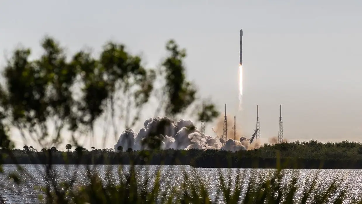 Een raket stijgt met veel rook en vuur op vanaf een lanceerplatform. 