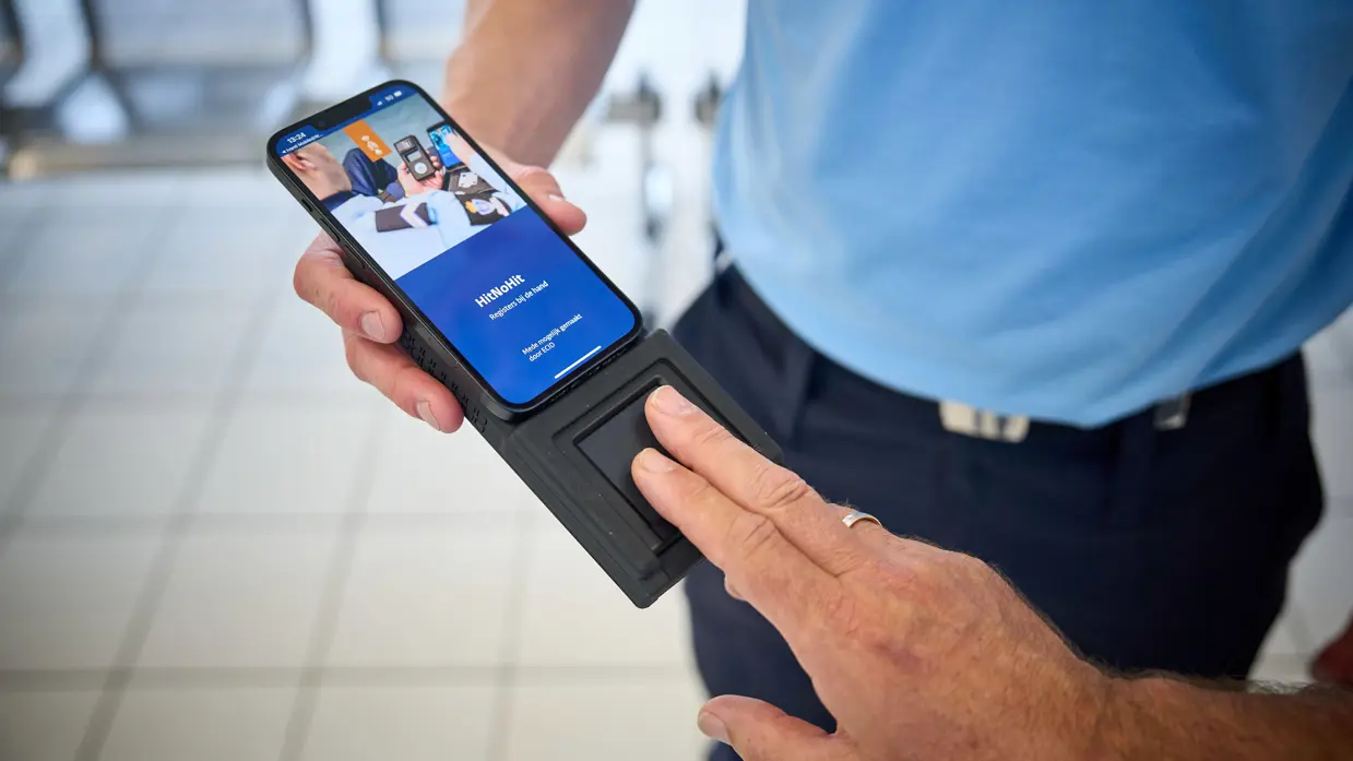Een passagier legt 2 vingers op een mobiele scanner.