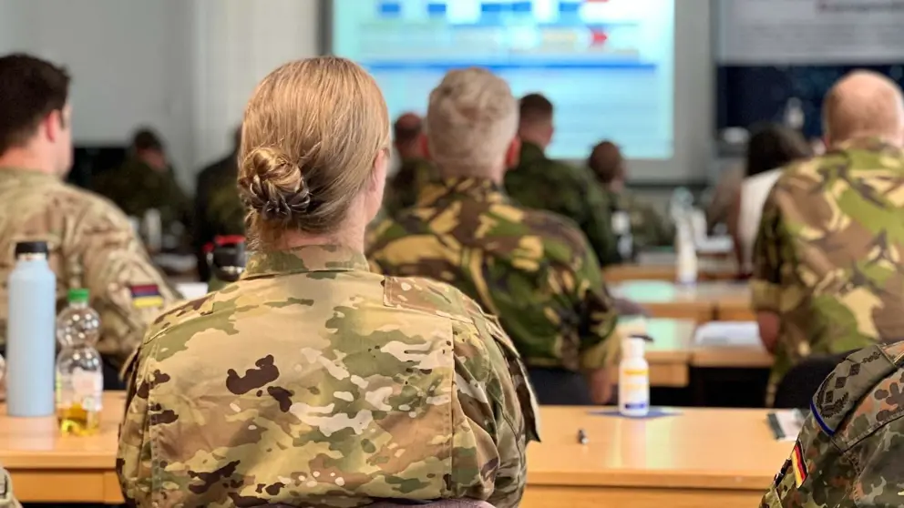 Militairen op de rug gezien tijdens presentatie in vergaderruimte.