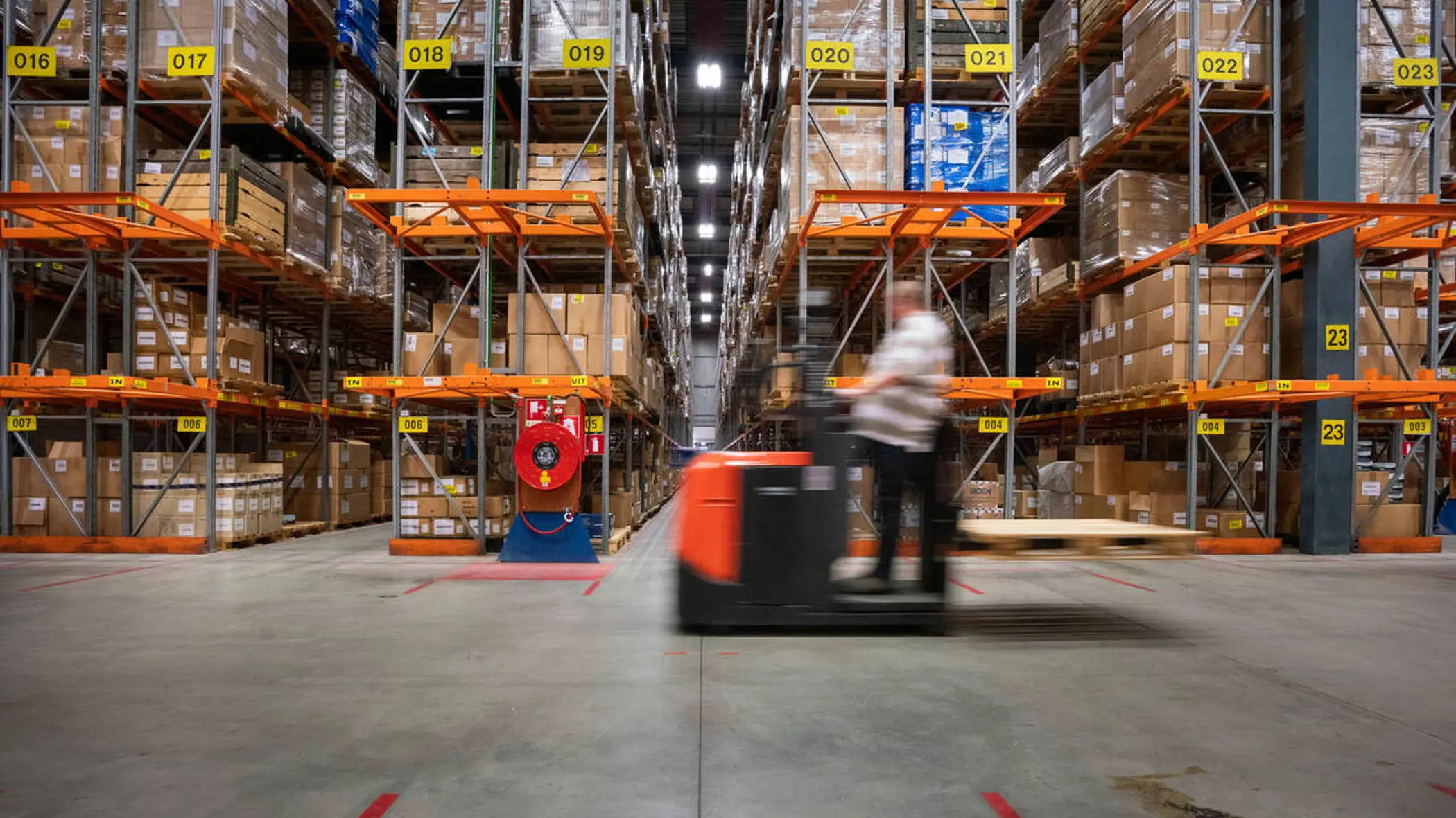 Een man rijdt op een voertuig door een opslagdepot.