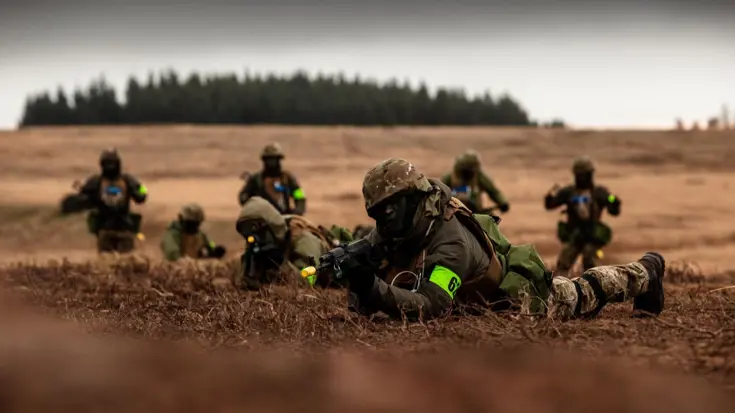 Militairen liggend in het veld, ze richten hun wapens.