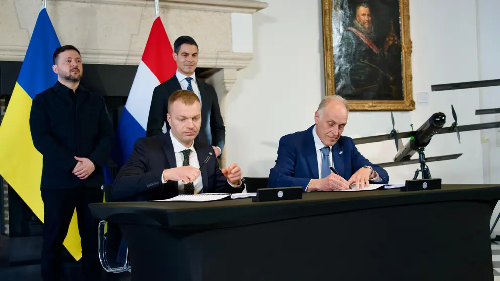 Het contract wordt ondertekend. Daarachter staan Zelensky en Jetten.