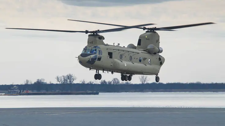 Militaire transporthelikopter hangt vlak boven de grond.