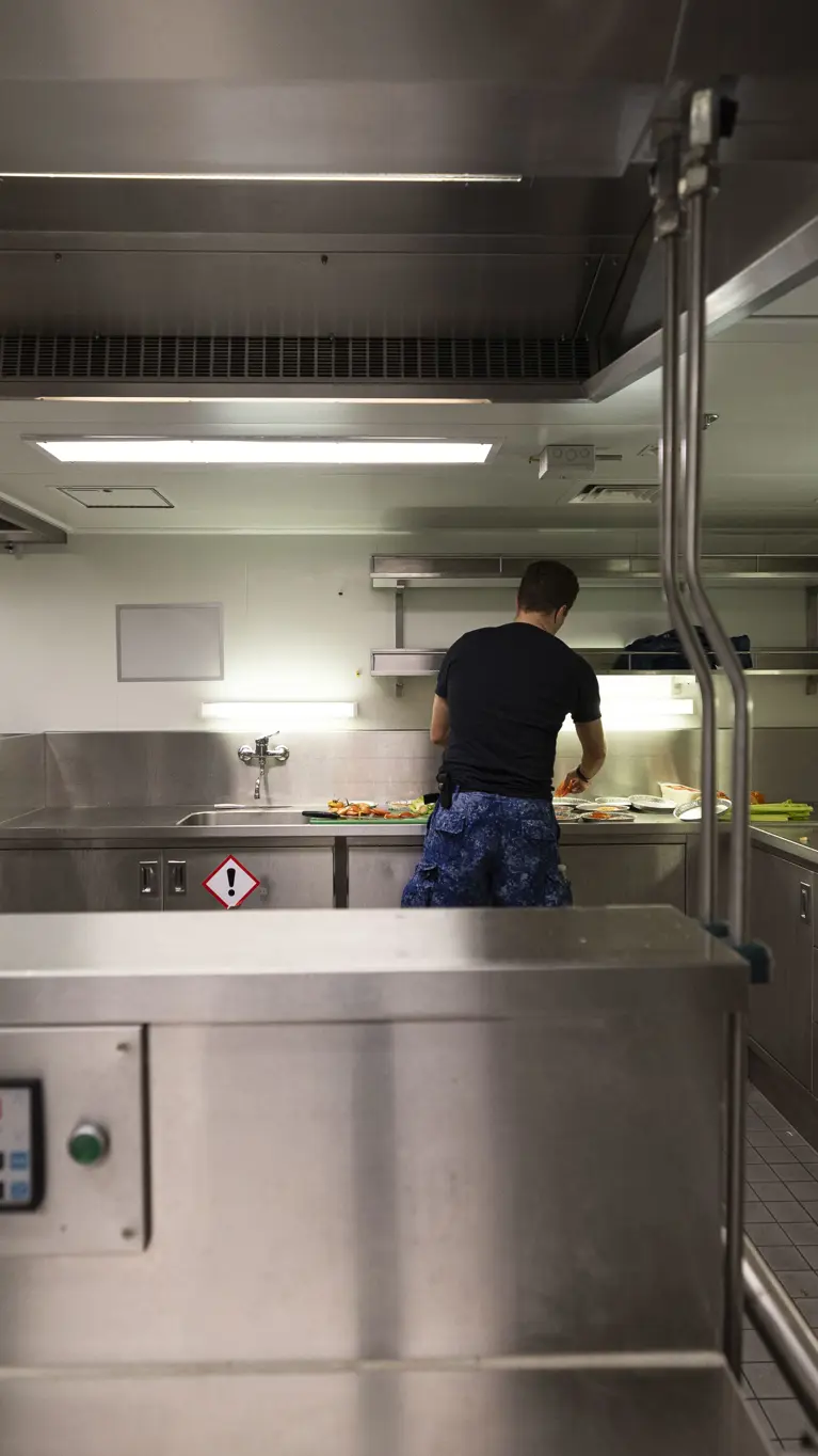 Een kok is aan het werk in een chromen keukenomgeving.