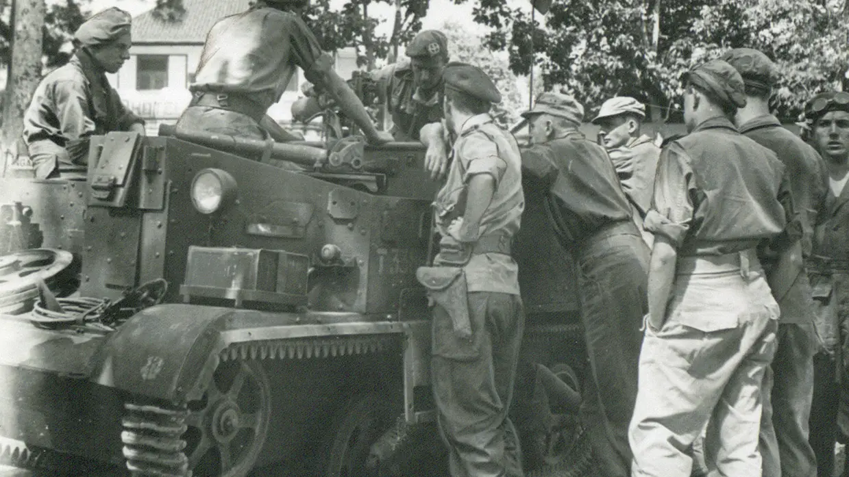 Zwart-witfoto met militairen die rond een pantservoertuig staan.