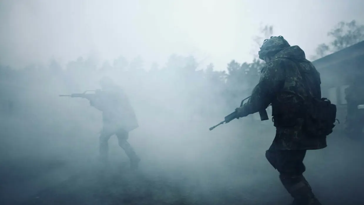 Militair met wapen loopt door veld vol met rook tijdens oefening.