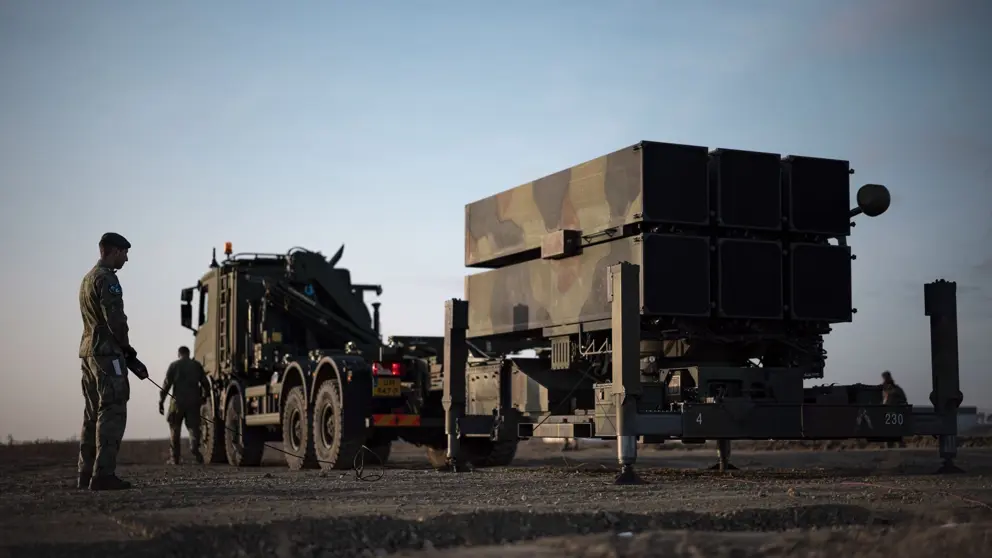 2 militairen staan bij een luchtafweersysteem. 