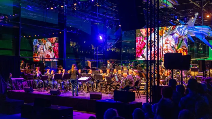 Een band op het podium en op de voorgrond hoofden van het publiek.