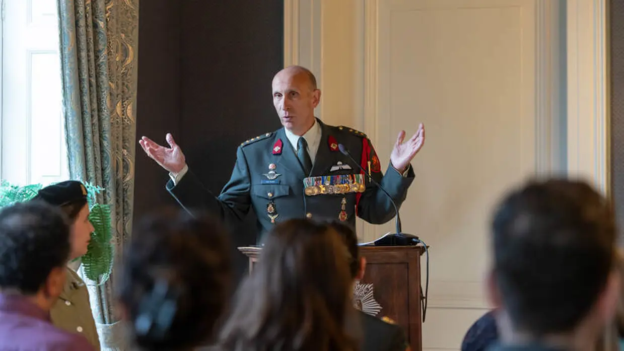 Militair spreekt zaal toe tijdens ceremonie.