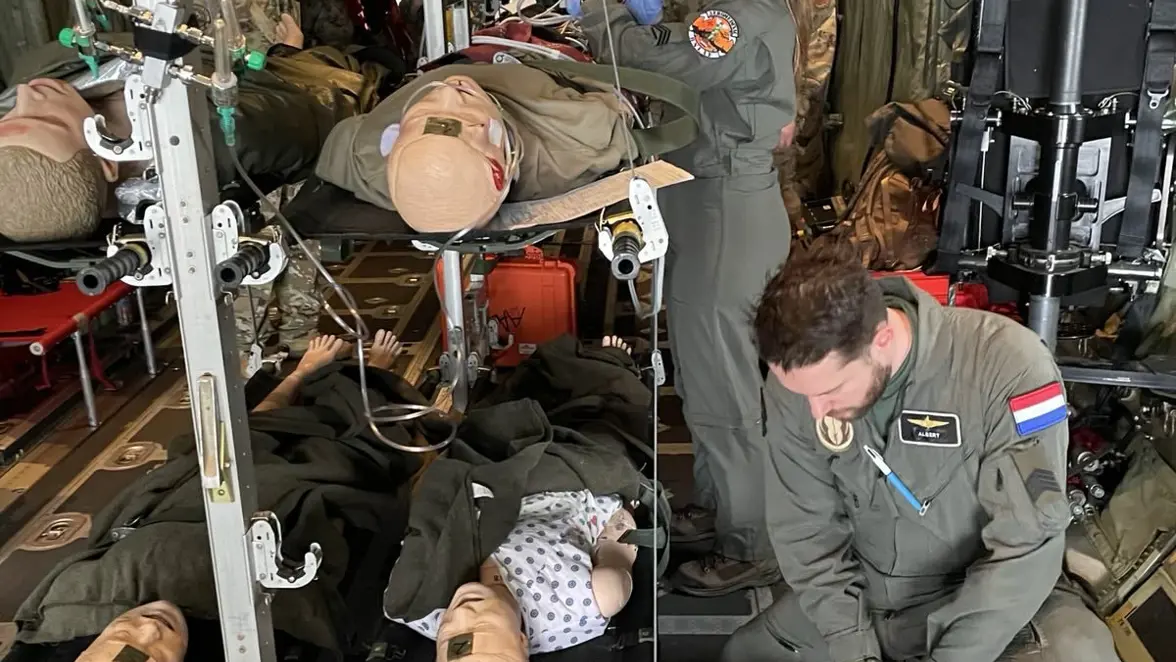 Luchtmachtmilitairen staan in het vrachtruim van een C-130 en verzorgen patiënten op brancards.