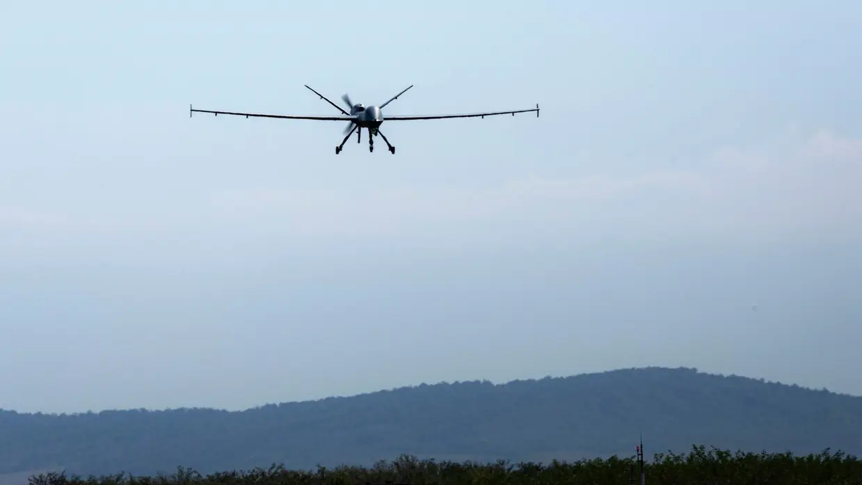 Een MQ-9 Reaper in de lucht in Roemenië met op de achtergrond een berg