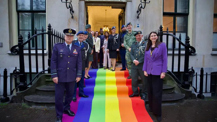 Militairen en burgerpersoneel van Defensie staat naast een regenboogloper.