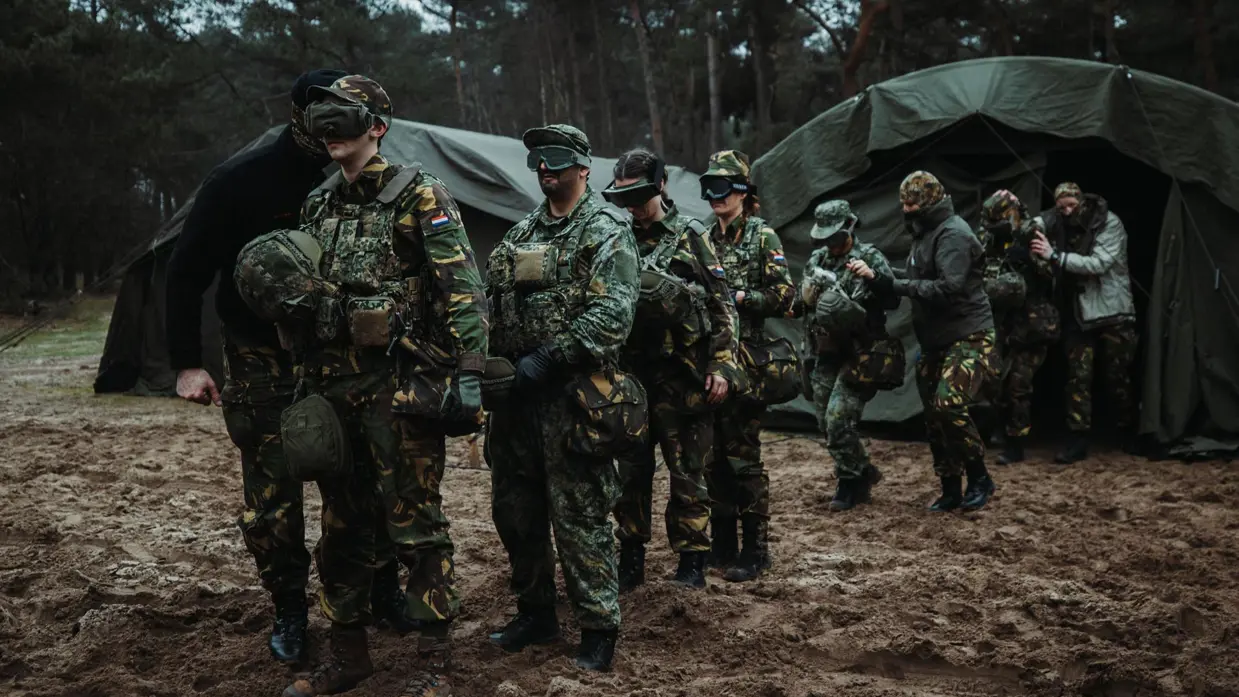 Soldaten geblinddoekt in bos voor tent.