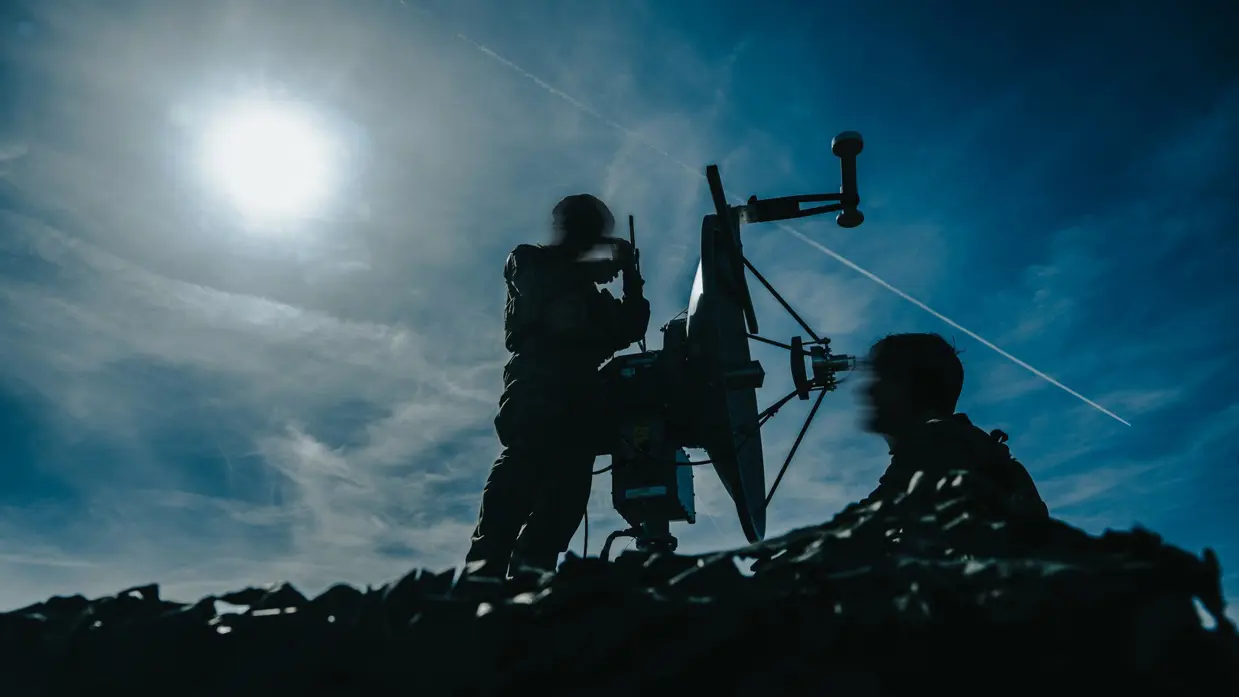 Silhouetten van militairen met een wapen.