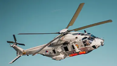 Het voordek van Zr.Ms. Snellius een kraan. En een NH90 voorzien van oefentorpedo in de lucht.