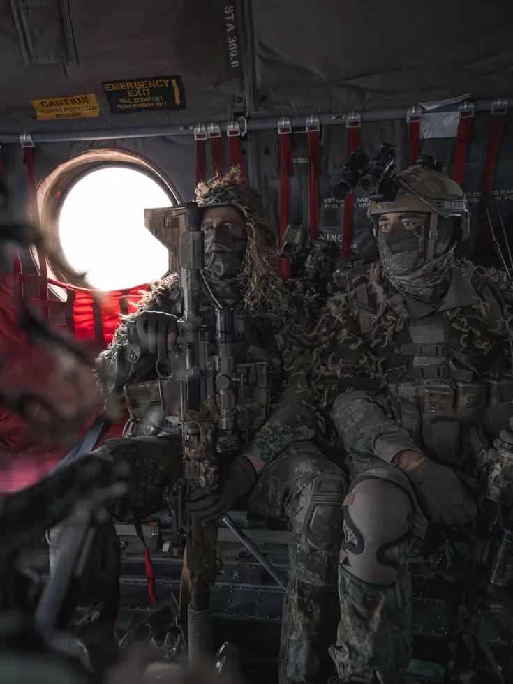 Twee militairen met wapens zittend in een Chinook.
