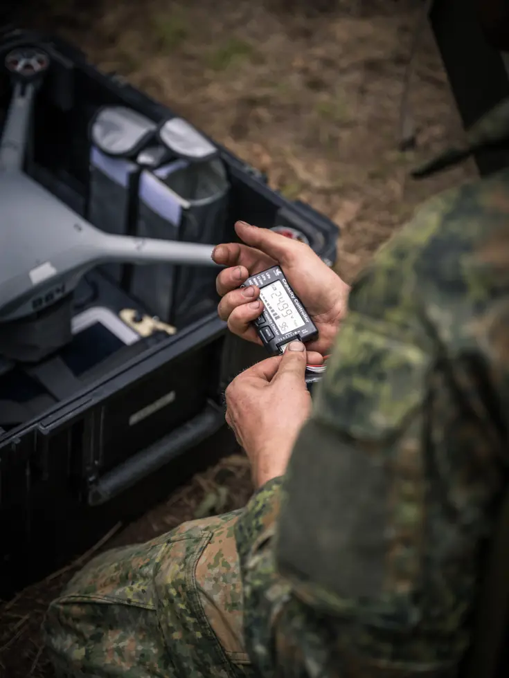 Militair controleert een dronecomponent tijdens voorbereiding in het veld.