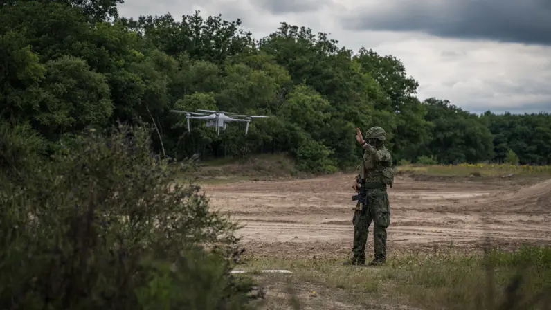 Militair begeleidt een drone tijdens inzet in het veld. 