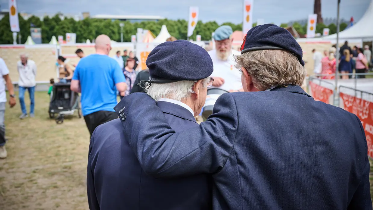 Twee veteranen met hun armen om elkaar op het Malieveld in Den Haag.