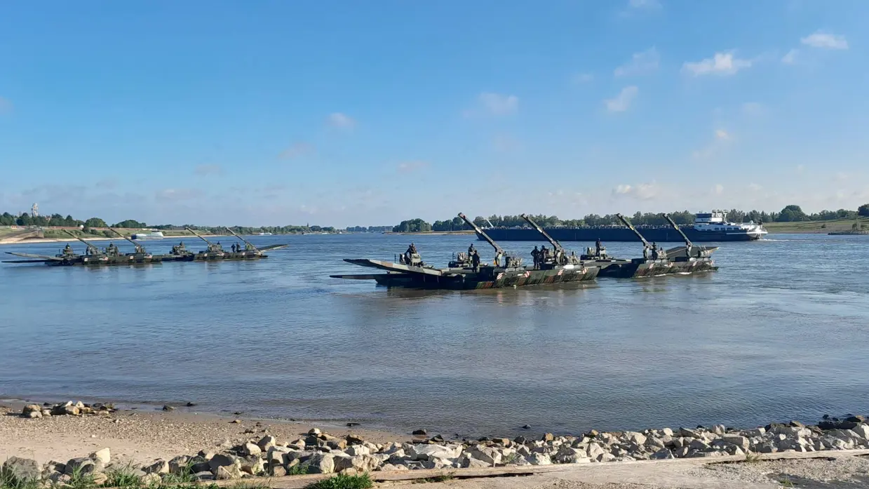 Militairen staan op pontons in een rivier.