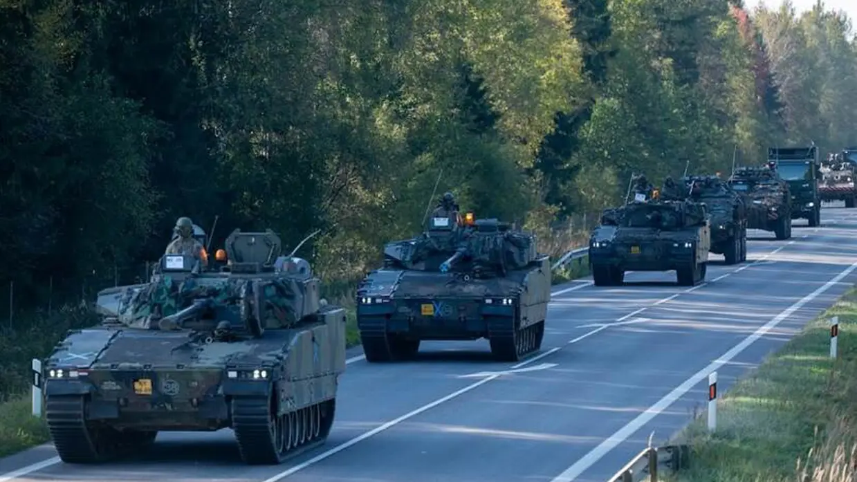 Militaire voertuigen in kolonne op een Litouwse weg.