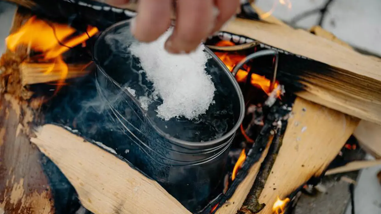 Militair smelt sneeuw in een ketel om kokend water te maken.