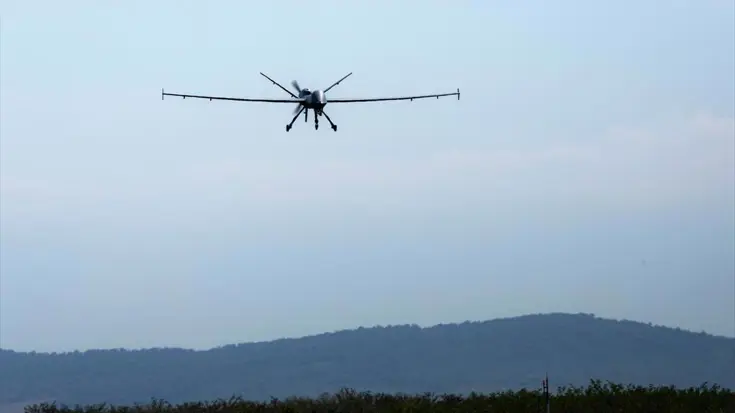 Een Reaper in volle vlucht boven heuvelachtig gebied. 