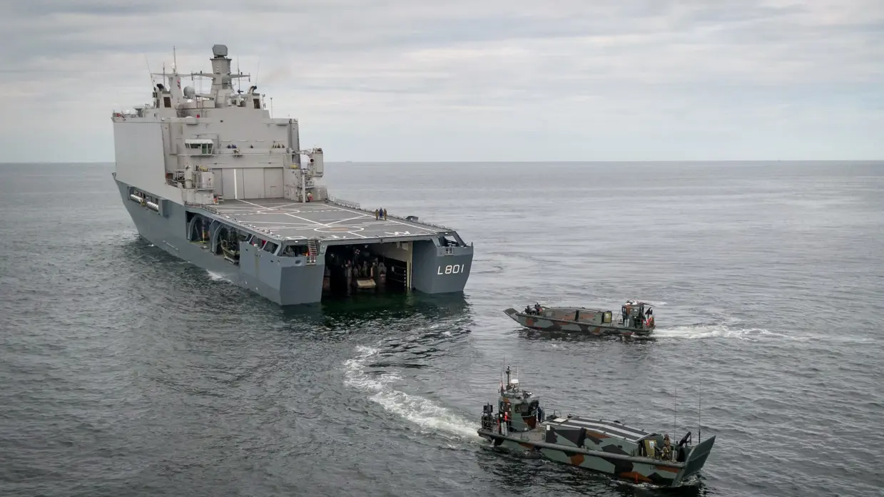 Marineschip op zee met 2 kleinere schepen achter het schip.
