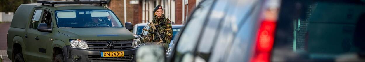 Reservist naast terreinwagen Defensie in straatbeeld.