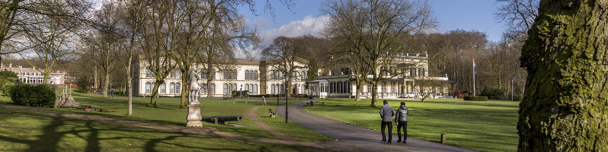 2 bezoekers lopen over de oprijlaan van het landgoed naar museum Bronbeek.