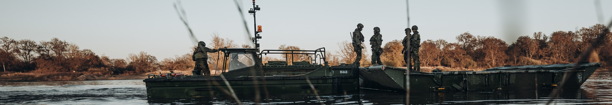 Militairen staand op een deel van een pontonbrug in het water.