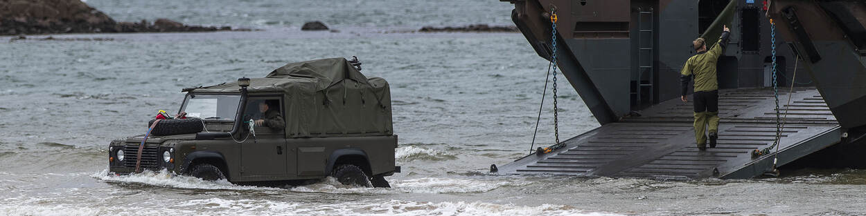 Jeep rijdt door zee, na verlaten marineschip.