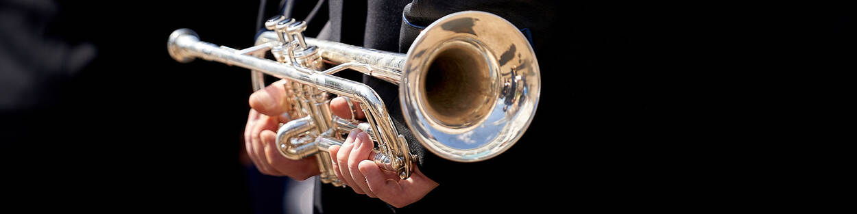 Een muzikant houdt een trompet in zijn hand.