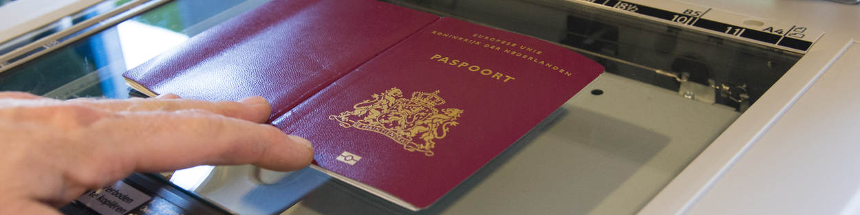 Persoon legt een paspoort op de glasplaat van een kopieerapparaat.