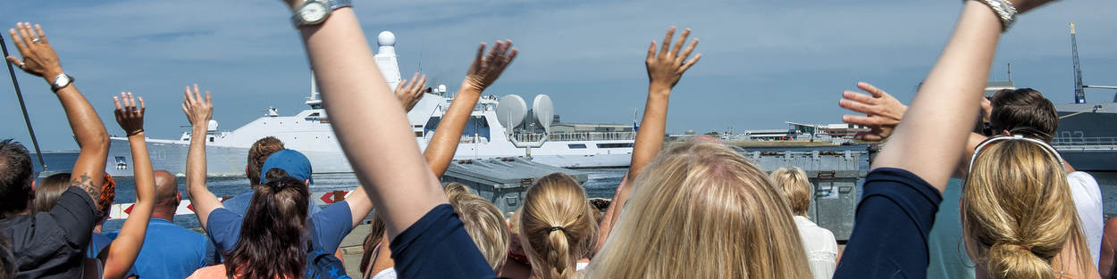 Thuisblijvers zwaaien marineboot uit.