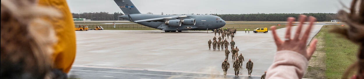 Militairen lopen op landingsbaan Vliegbasis Eindhoven, hun wachtend thuisfront zwaait.