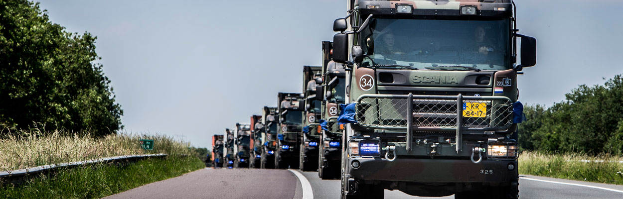 Kolonne vrachtwagens van Defensie op Nederlandse weg.