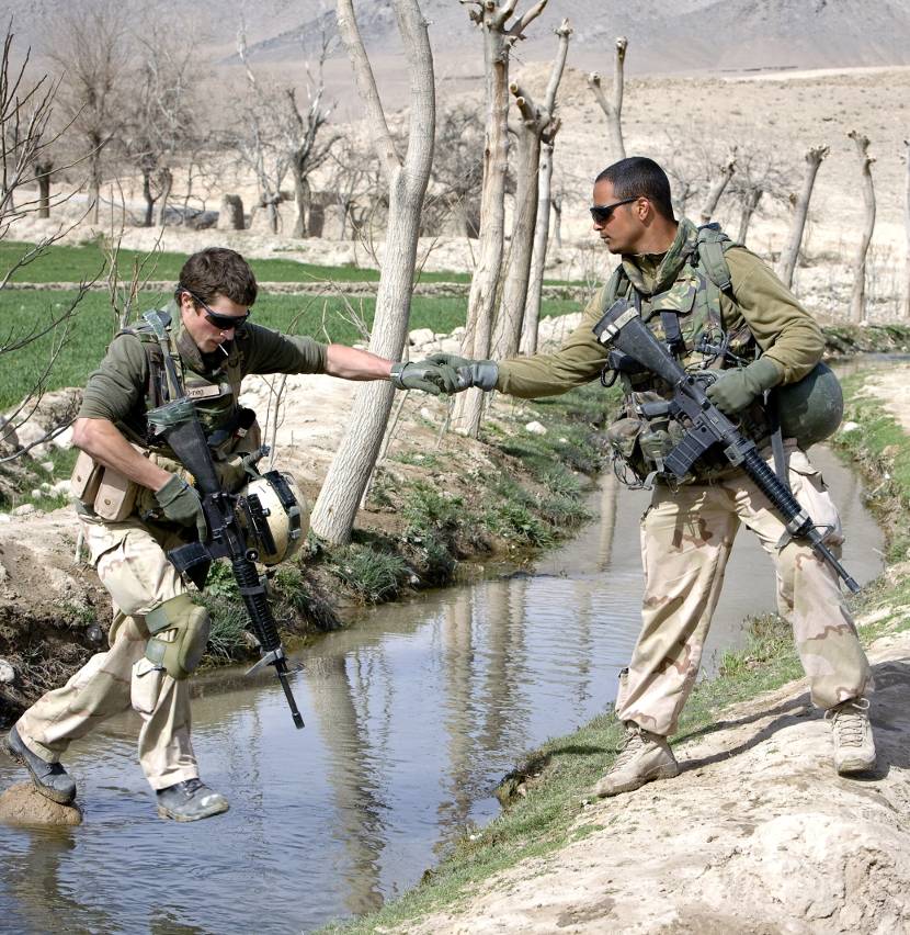 Dutch soldiers lend each other a helping hand while crossing a stream.