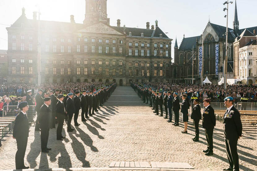Militairen staan opgesteld op de Dam in Amsterdam, publiek erachter.