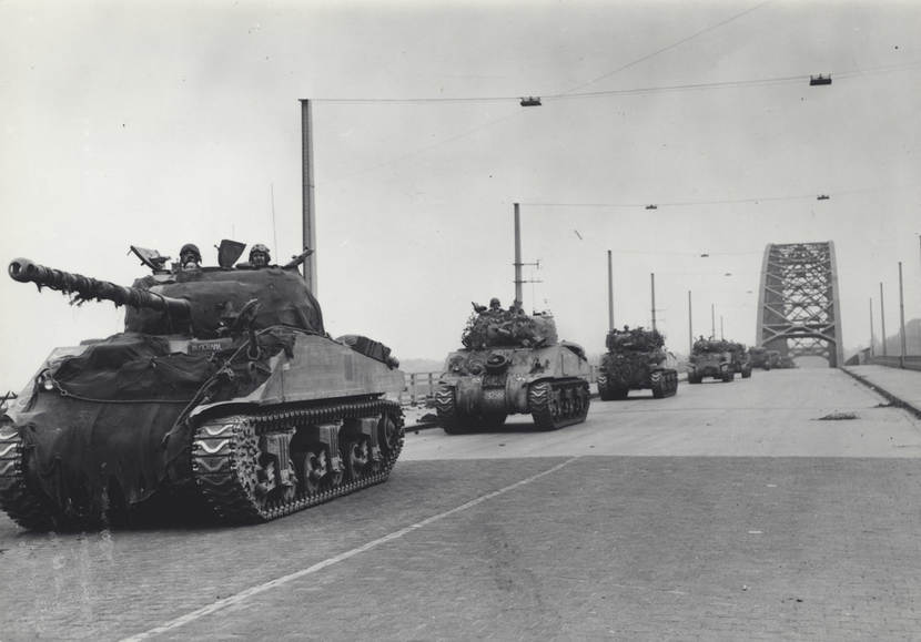 Zwart-witfoto: een colonne Shermantanks rijdt over de Waalbrug bij Nijmegen.
