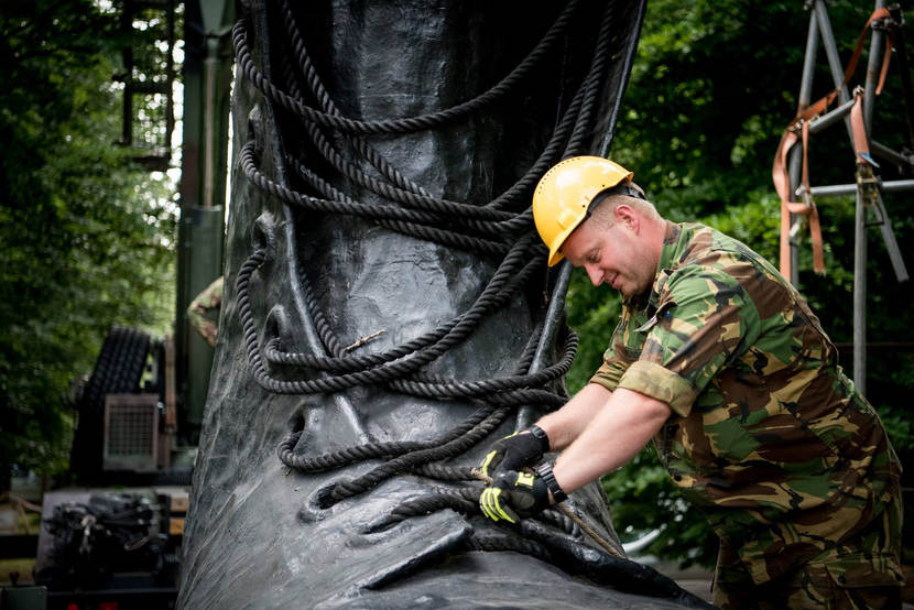 Een militair legt de laatste hand aan 1 van de grote kisten die de poort van Kamp Heumensoord vormt.