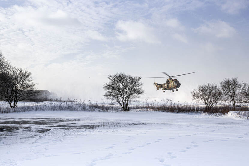 Militaire helikopter boven sneeuwvlakte.