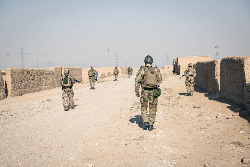 Militairen patrouilleren in een stoffige straat in Afghanistan.