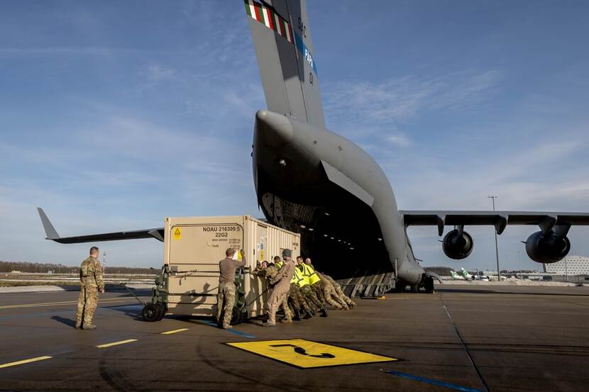 Militairen laden een container in een C-17-transportvliegtuig.