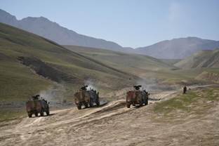 3 militaire voertuigen rijden in de bergen van Afghanistan.