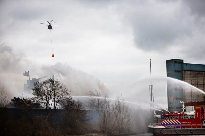 Een helikopter blust met een bambi bucket een brand.