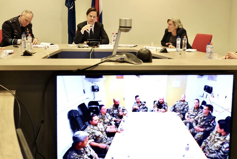 Premier en minister kijken op scherm met militairen in missiegebied.